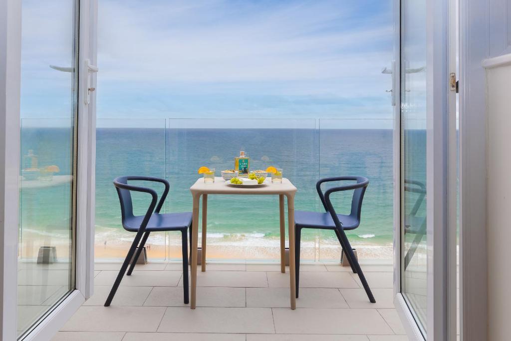 a table and two chairs in a room with a view of the ocean at Wavetop in St Ives