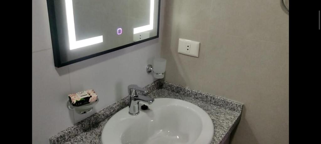 ein Bad mit einem Waschbecken, einem Spiegel und einem Fenster in der Unterkunft Departamento Ambar in Cochabamba