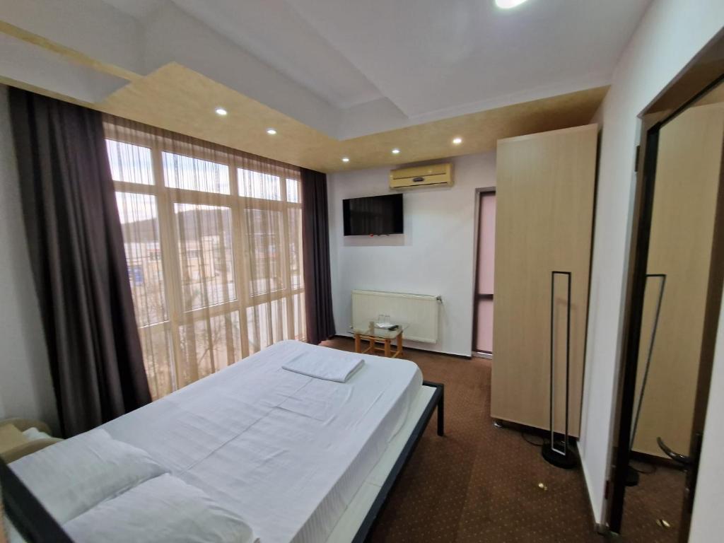 a bedroom with a large bed and a large window at Pensiunea Escape in Iaşi