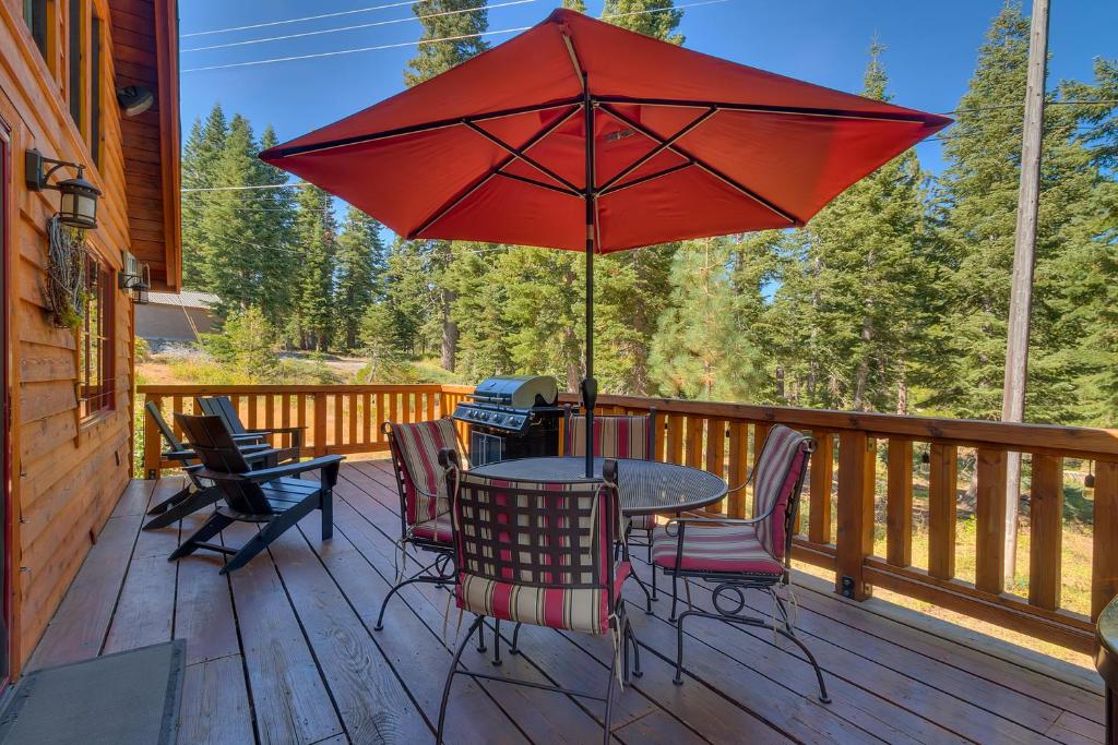 une table et des chaises sur une terrasse avec un parasol rouge dans l'établissement Lazy Bear, à Tahoe City