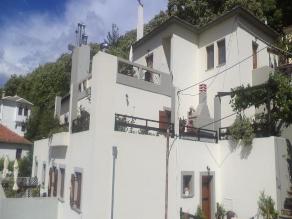 - un bâtiment blanc avec des personnes sur un balcon dans l'établissement Guesthouse Kallisti, à Anilio Pelion