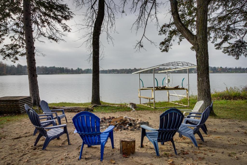 a group of chairs sitting in the sand near a lake at Waterfront Brainerd Cabin with Rice Lake Access! in Brainerd