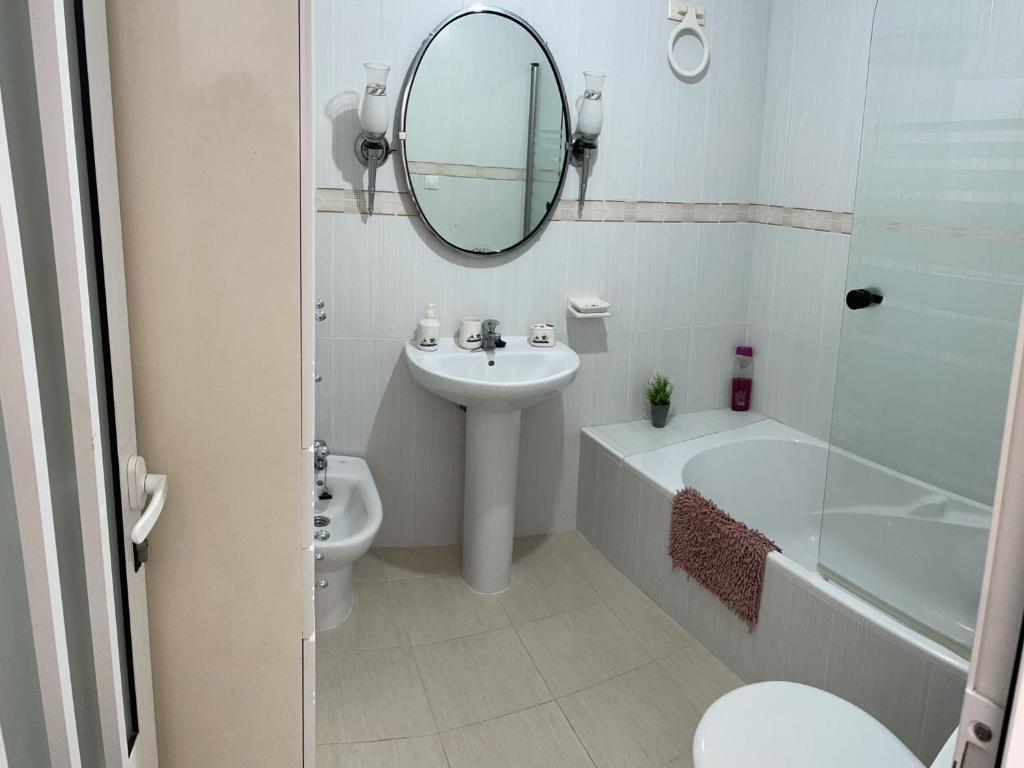Baño blanco con lavabo y espejo en Alojamiento Orellana, en Orellana la Vieja