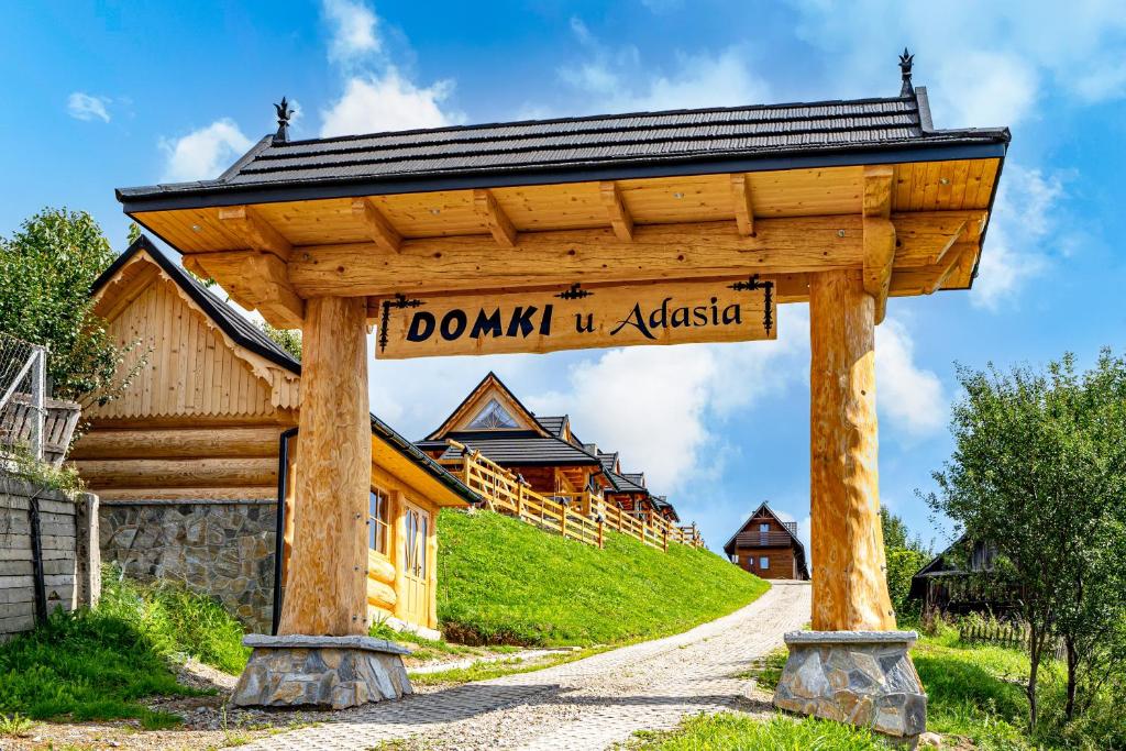 ein Holztor mit einem Schild vor einem Haus in der Unterkunft Domki u Adasia in Krośnica