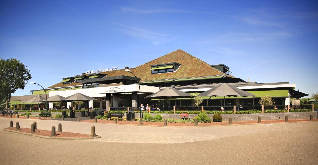 ein großes Gebäude mit Sonnenschirmen davor in der Unterkunft Van der Valk Hotel Akersloot / A9 ALKMAAR in Akersloot