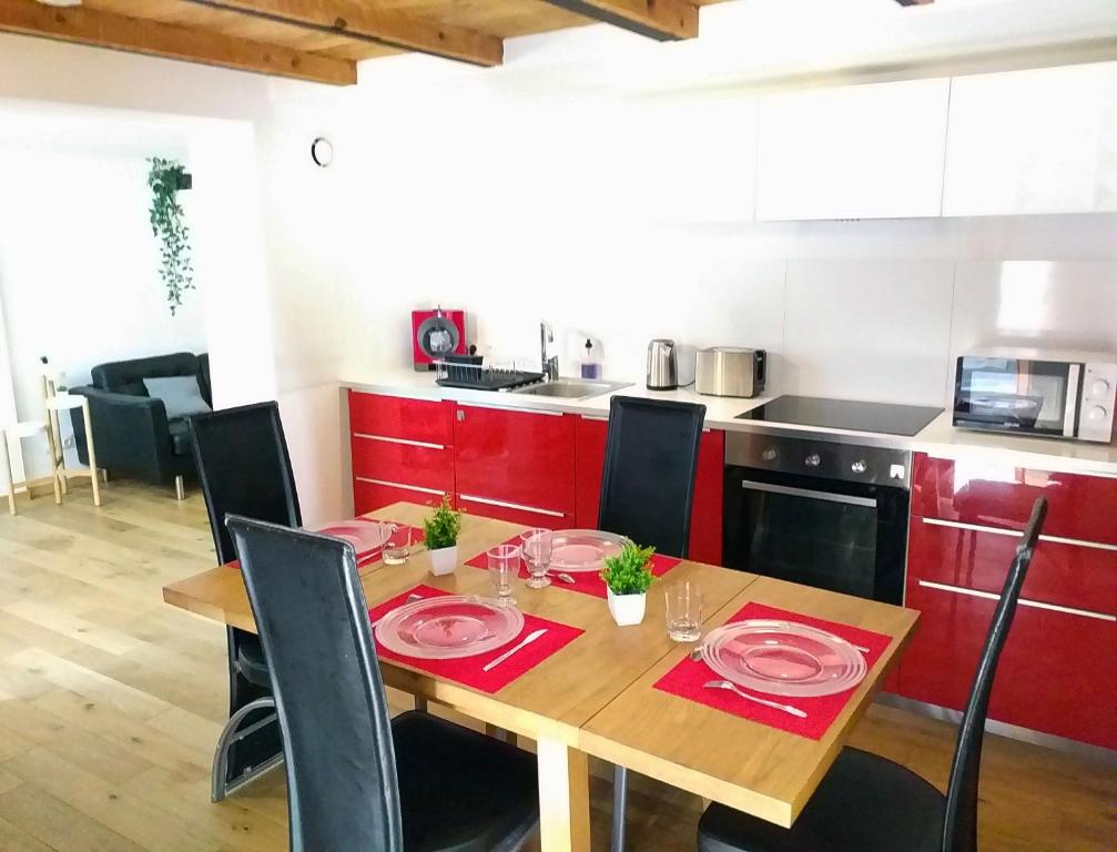 a kitchen with a wooden table with red cabinets at Le Paisible - Gare - Duplex - Garage privé - Netflix in Grenoble