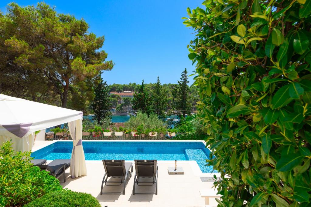 a swimming pool with chairs and a white umbrella at APARTMANI MARIS in Milna