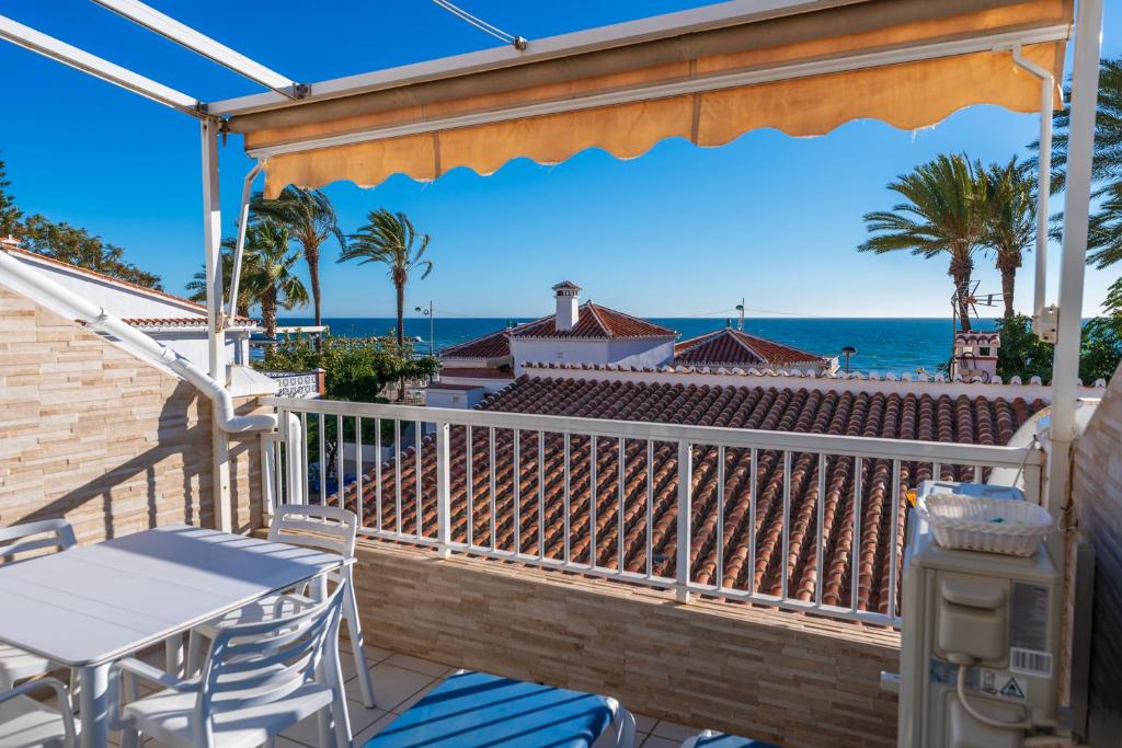 een balkon met een tafel en stoelen en de oceaan bij Beach Bungalow Torrox in Torrox