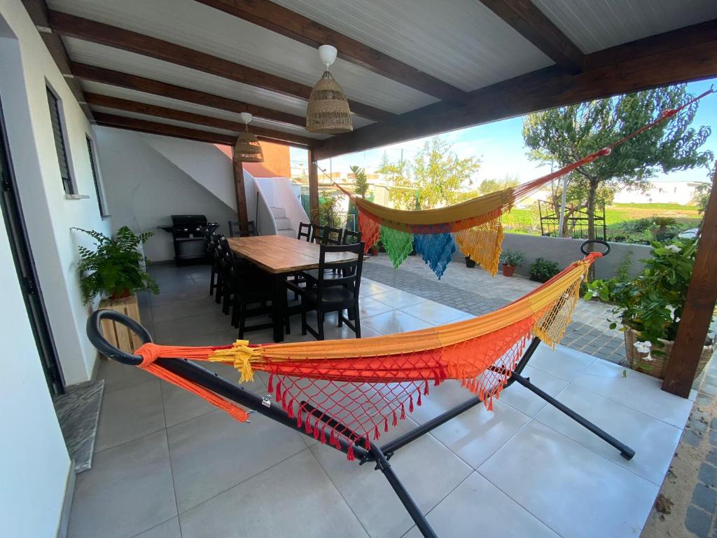 a hammock on a patio with a table and chairs at Casa Cova da Onça in Olhão