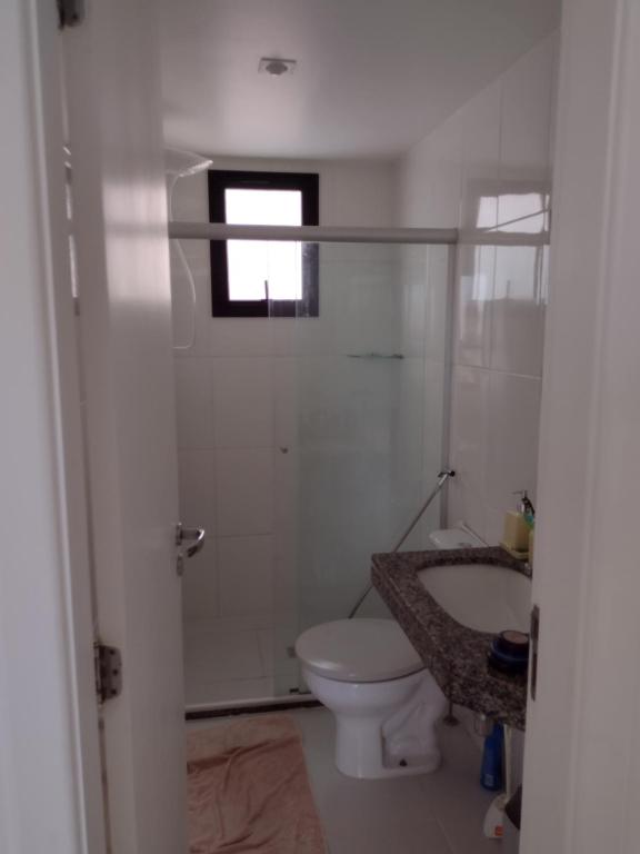 a bathroom with a toilet and a sink and a window at Apt Estrada do coco- Lauro de Freitas in Lauro de Freitas