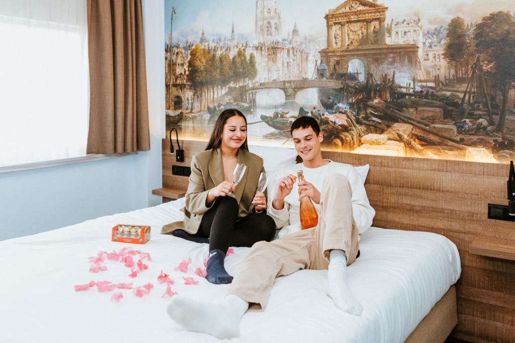 a man and a woman sitting on a bed at Rotterdam Teleport Hotel in Rotterdam