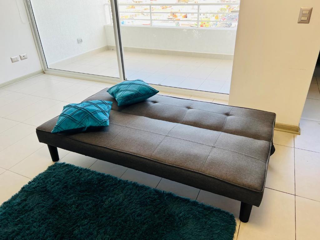 a brown couch with two blue pillows on it at Apartamento vista al mar in Iquique