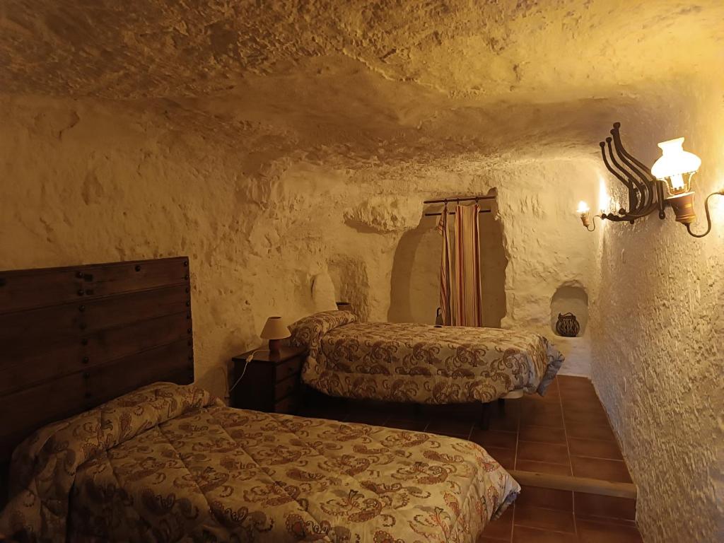 1 dormitorio con 2 camas en una habitación de piedra en Las Cuevas Del Abismo, en Alcalá del Júcar