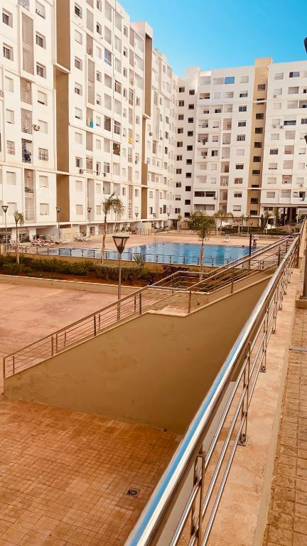 a walkway leading to a pool in a large building at Résidence avec piscine Agadir in Agadir