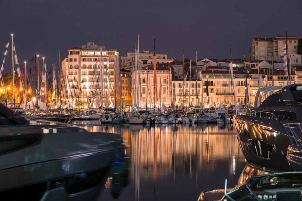 einen Hafen in der Nacht mit Booten im Wasser in der Unterkunft Vidal Croisette in Cannes