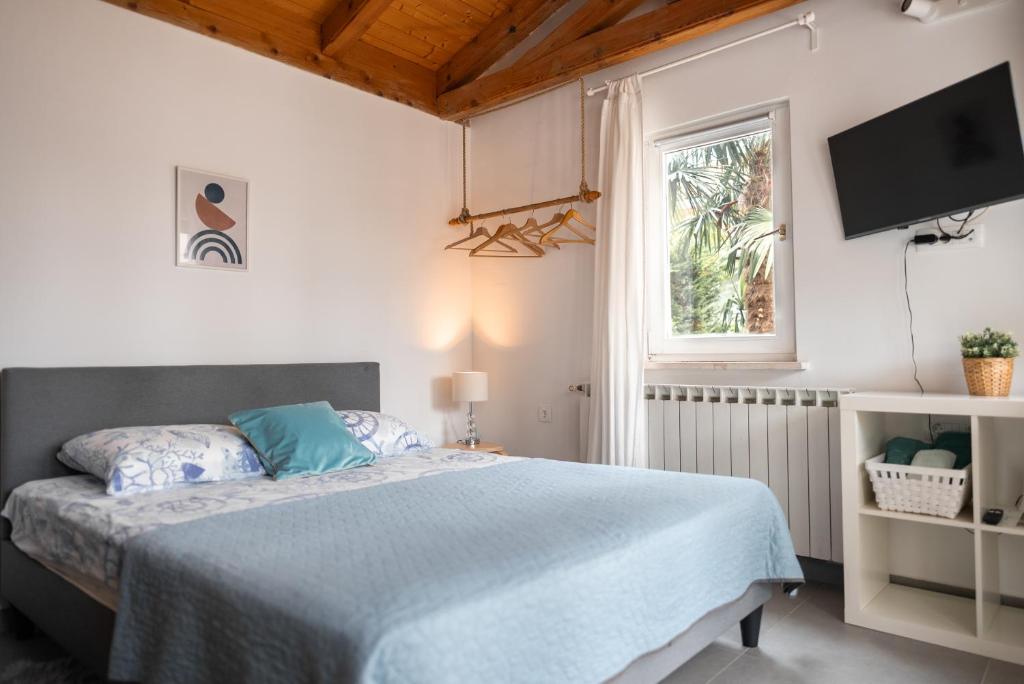 een slaapkamer met een bed en een tv aan de muur bij New cosy apartments with private parking in Opatija