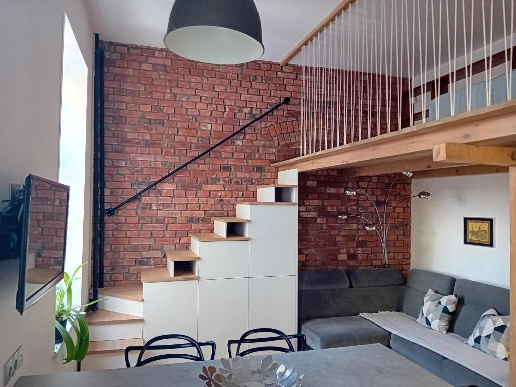 a brick wall in a living room with a staircase at Kawalerka z antresolą do wzięcia in Gdańsk