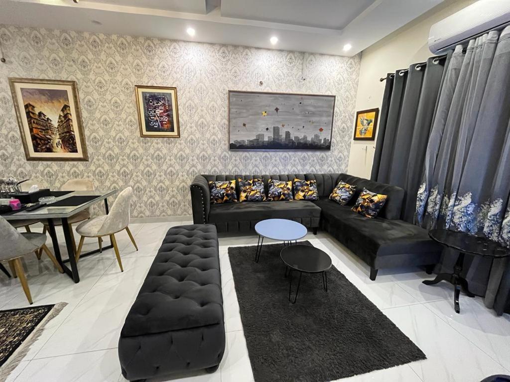 sala de estar con sofá negro y mesa en Vacation Villa en Lahore