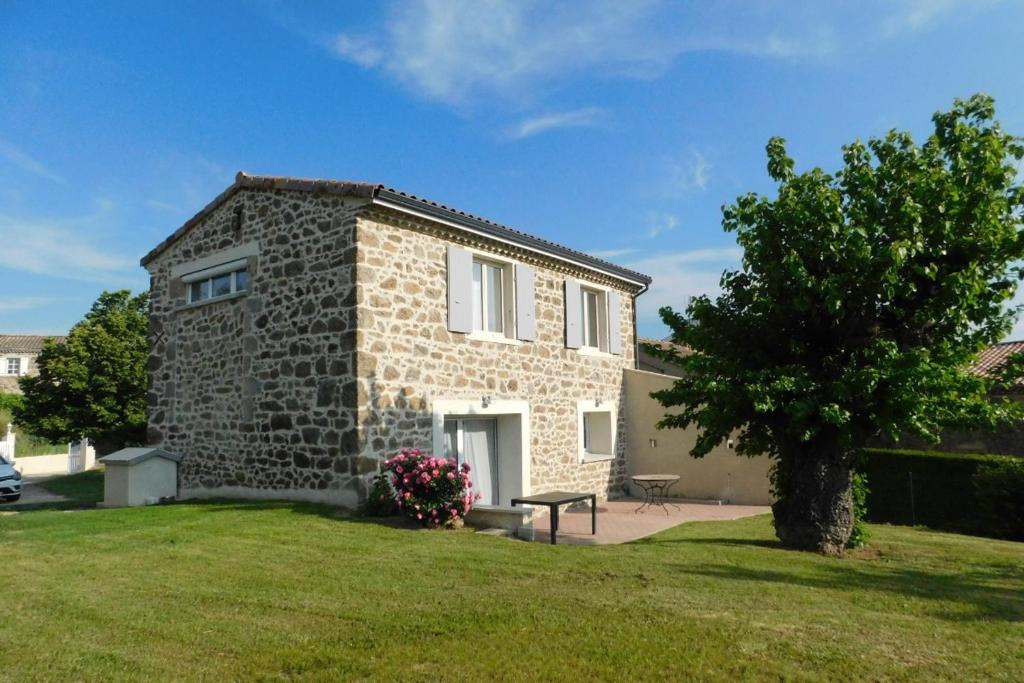 una casa in pietra con un albero nel cortile di Gite des Perrines a Colombier-le-Cardinal