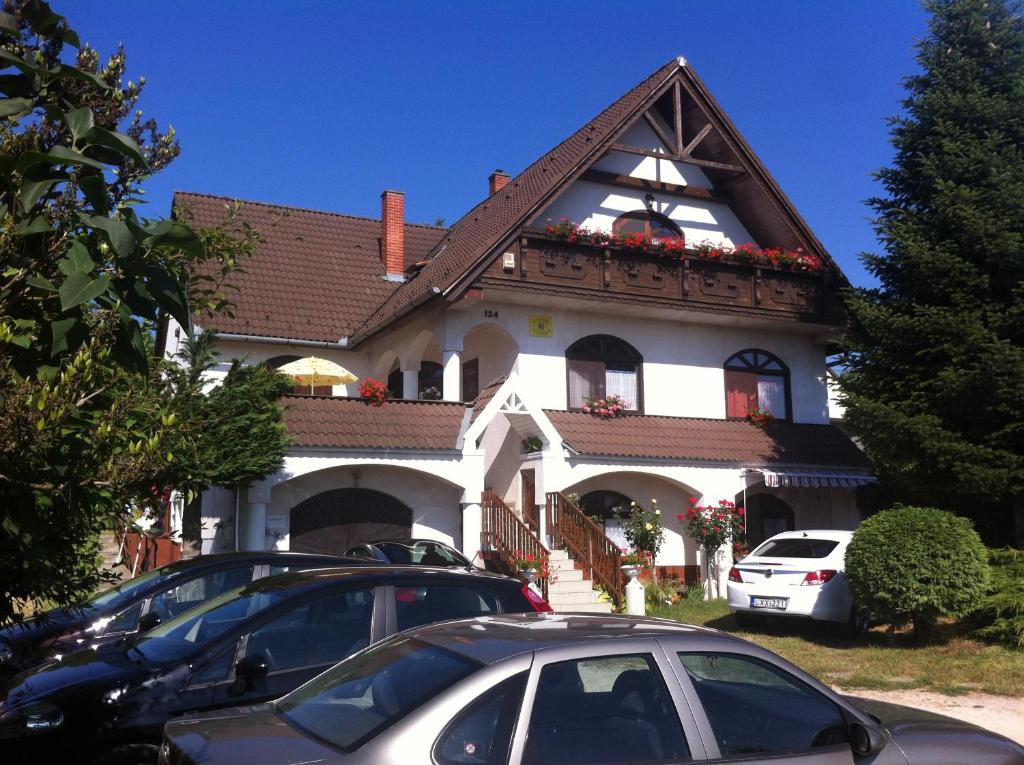 una gran casa blanca con coches estacionados frente a ella en Zsoli Vendégház, en Alsópáhok