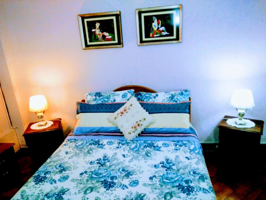 a bedroom with a blue and white bed with two lamps at the scandinavian in Valparaíso
