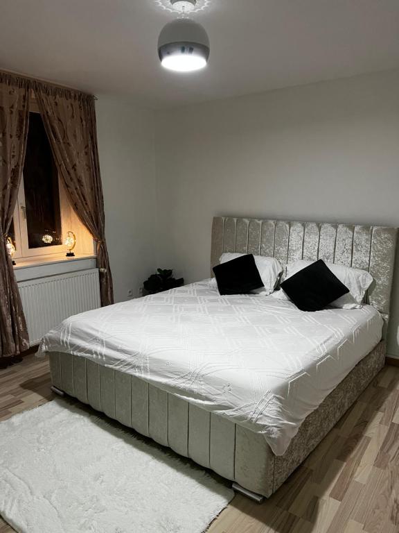 ein Schlafzimmer mit einem großen Bett mit weißer Bettwäsche und schwarzen Kissen in der Unterkunft Le clos Petite Venise in Colmar