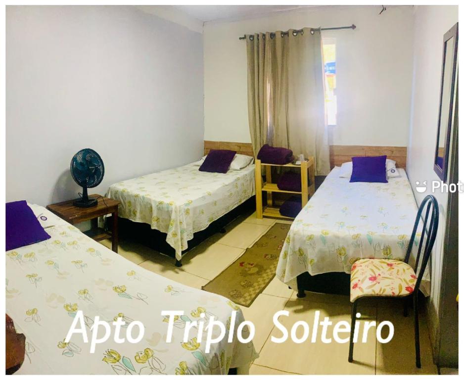 a room with two beds and a chair in it at Pousada Estrela Veadeiros in Alto Paraíso de Goiás