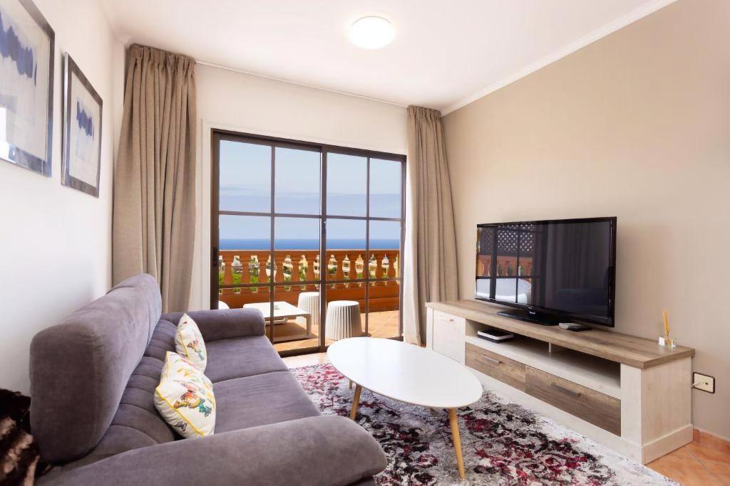 een woonkamer met een bank en een tv bij EDEN RENTALS Elite Palace Suites in Adeje
