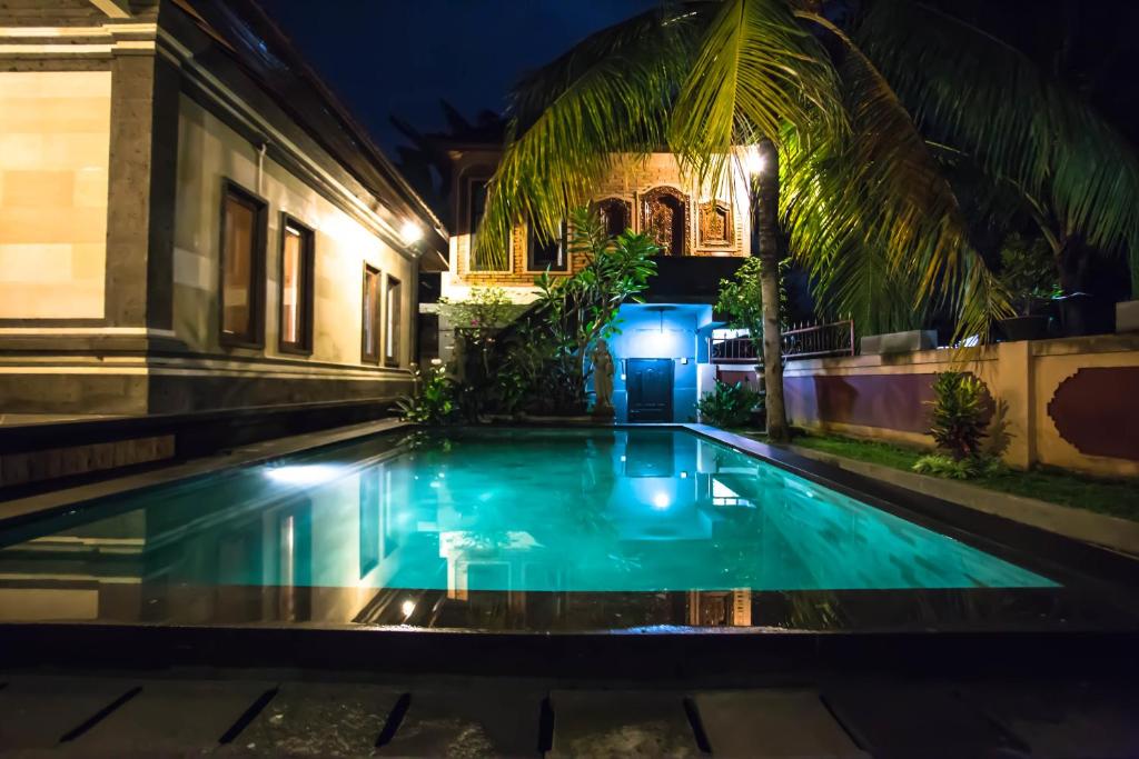a swimming pool in front of a house at night at Bali Culture Guesthouse in Ubud