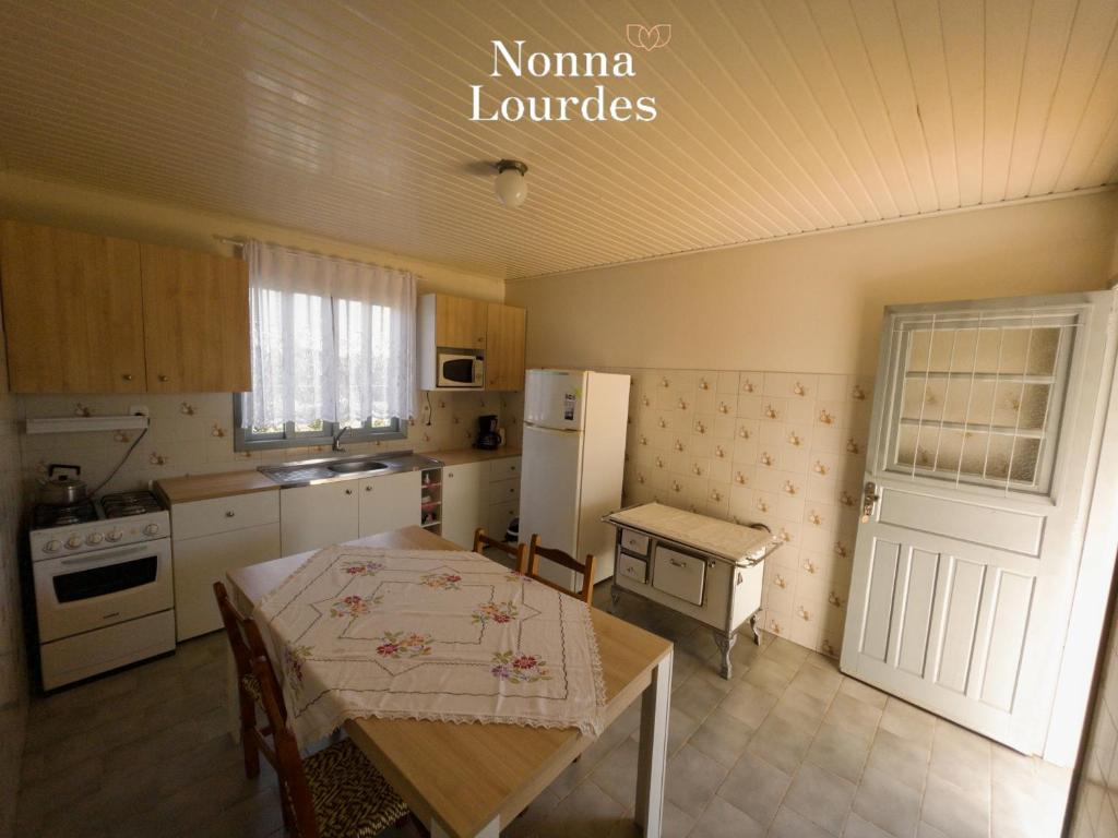 a kitchen with a table and a kitchen with a refrigerator at Recanto Nonna Lourdes - Vale dos Vinhedos in Bento Gonçalves