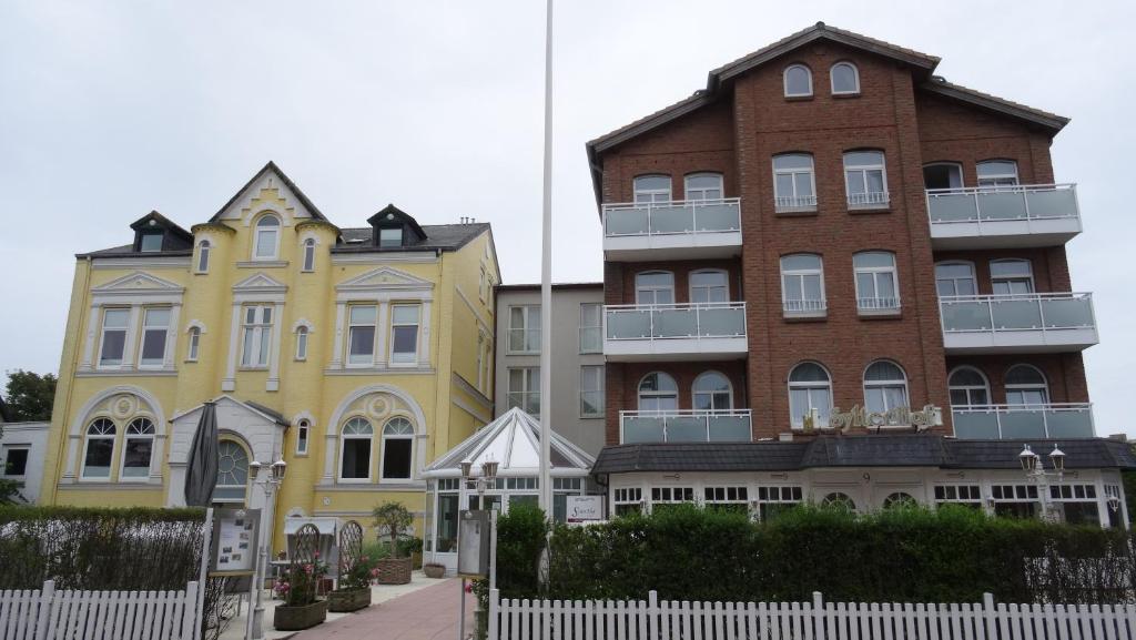 a group of buildings next to a white fence at Hotel Sylter Hof in Westerland