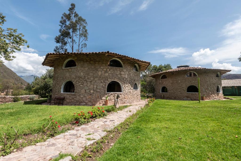 a stone building with two domes in a field at Bungalow RURU WASI in Urubamba