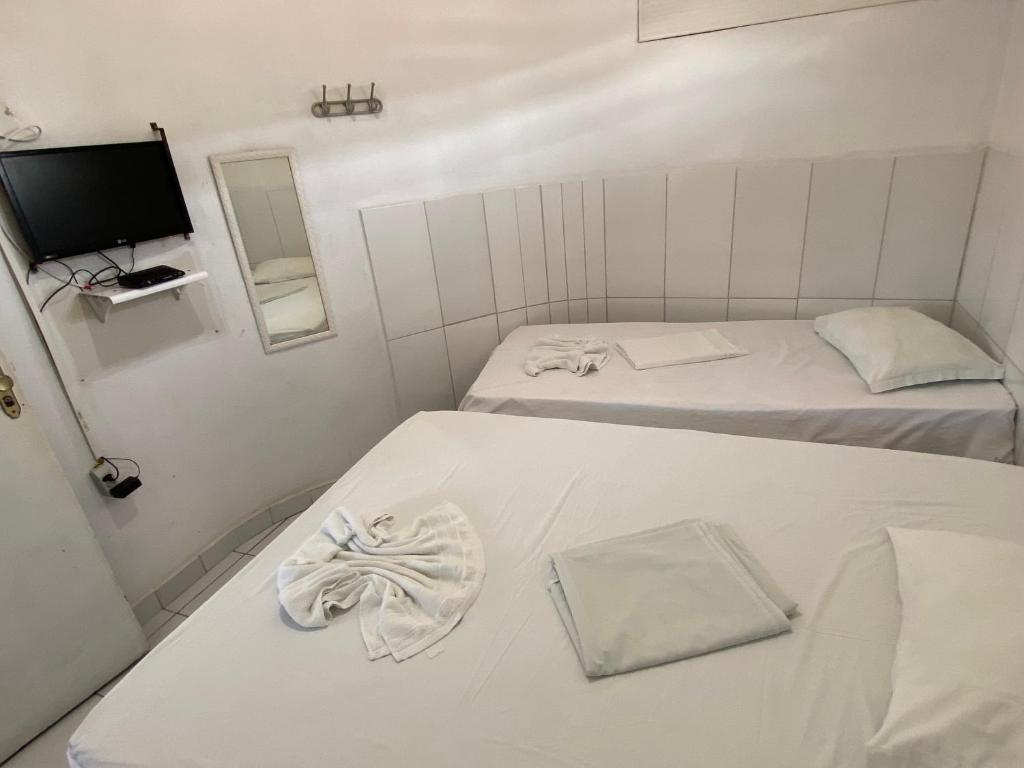 Habitación pequeña con 2 camas y TV. en Pousada Estrela Do Mar, en Maragogi