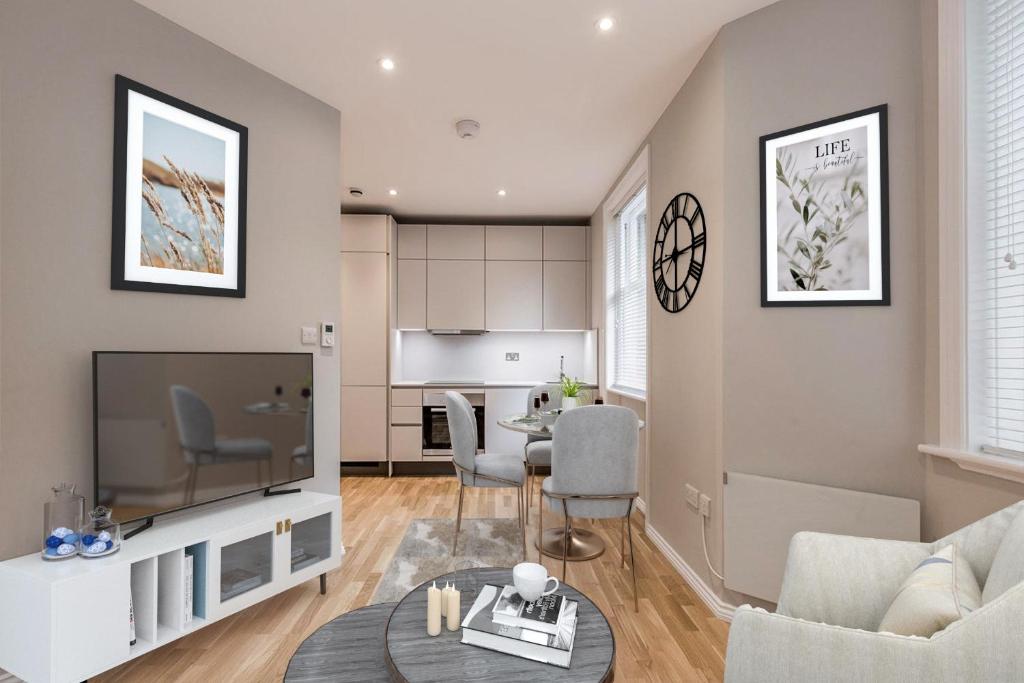ein Wohnzimmer mit einem großen TV und einem Tisch in der Unterkunft Kensington Olympia Apartment, Breakfast in London