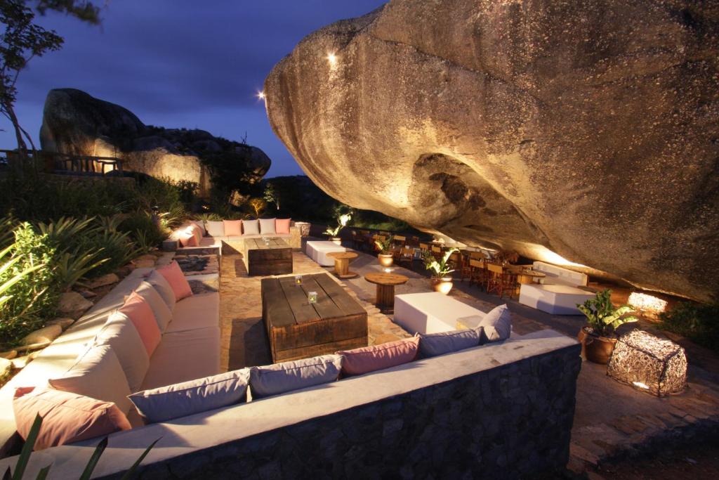 uma grande pedra sentada ao lado de um sofá e uma mesa em Pousada Villas da Serra em Serra de São Bento