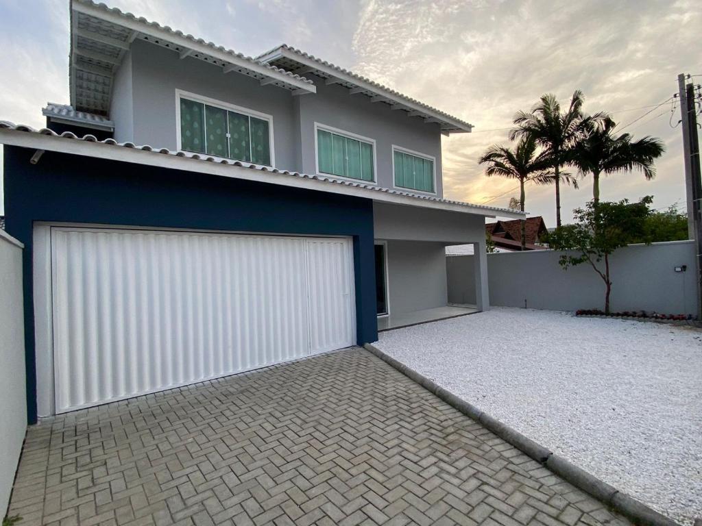 uma casa com uma garagem branca e azul em Pousada vale do paraíso em Navegantes