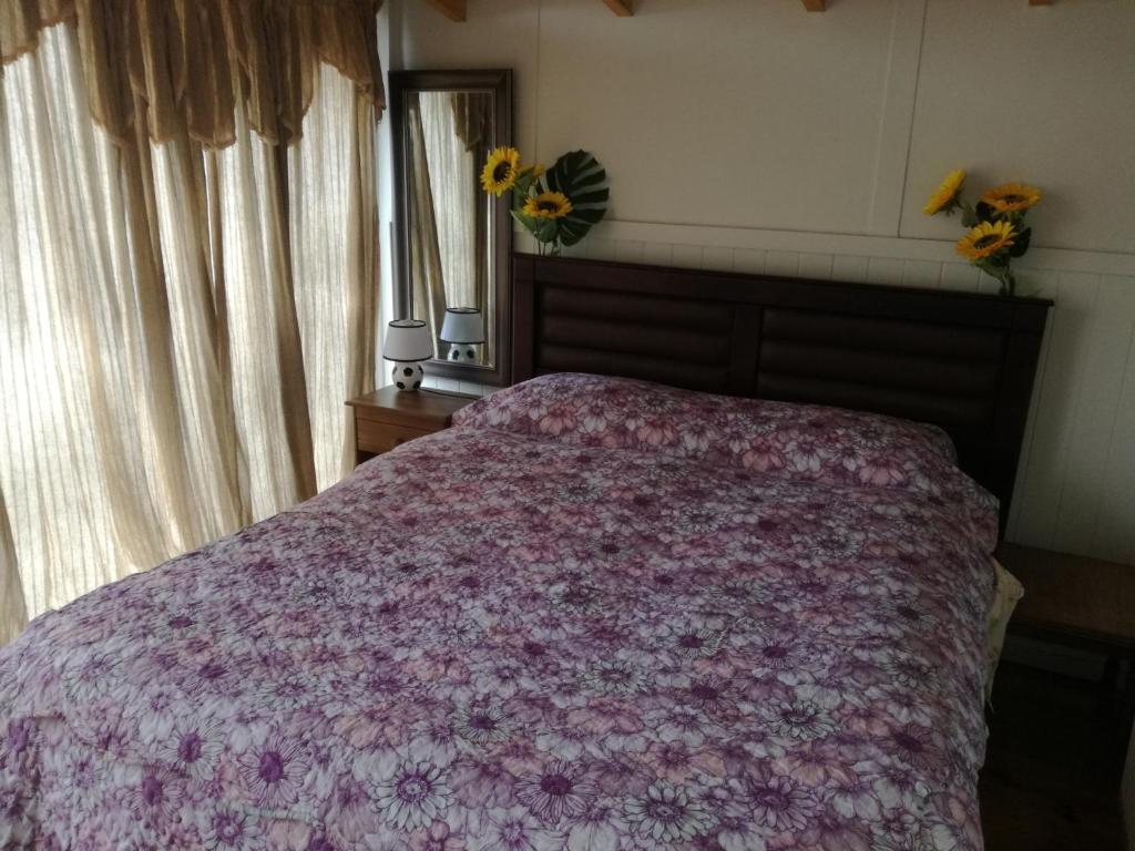 um quarto com uma cama com um cobertor roxo em Amacoa em Puerto Varas