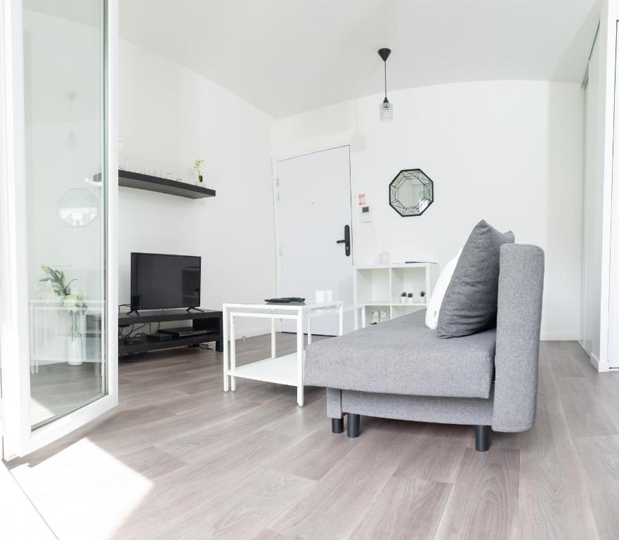 Sala de estar blanca con silla y escritorio en Hébergement touristique de luxe proche de Paris avec parking gratuit, situé face au parc des expositions et de l'aéroport du Bourget, à 15 min de CDG, en Le Blanc-Mesnil