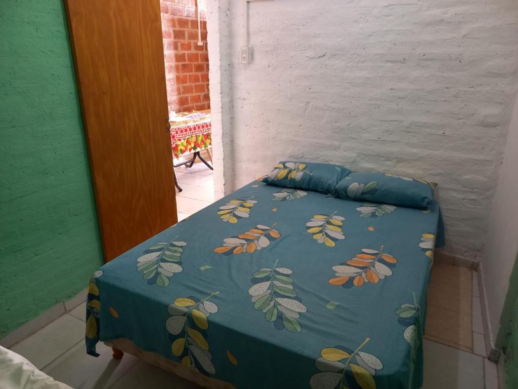 a bed with a blue comforter with leaves on it at ALQUILER TEMPORARIO LU-KA in Roque Sáenz Peña