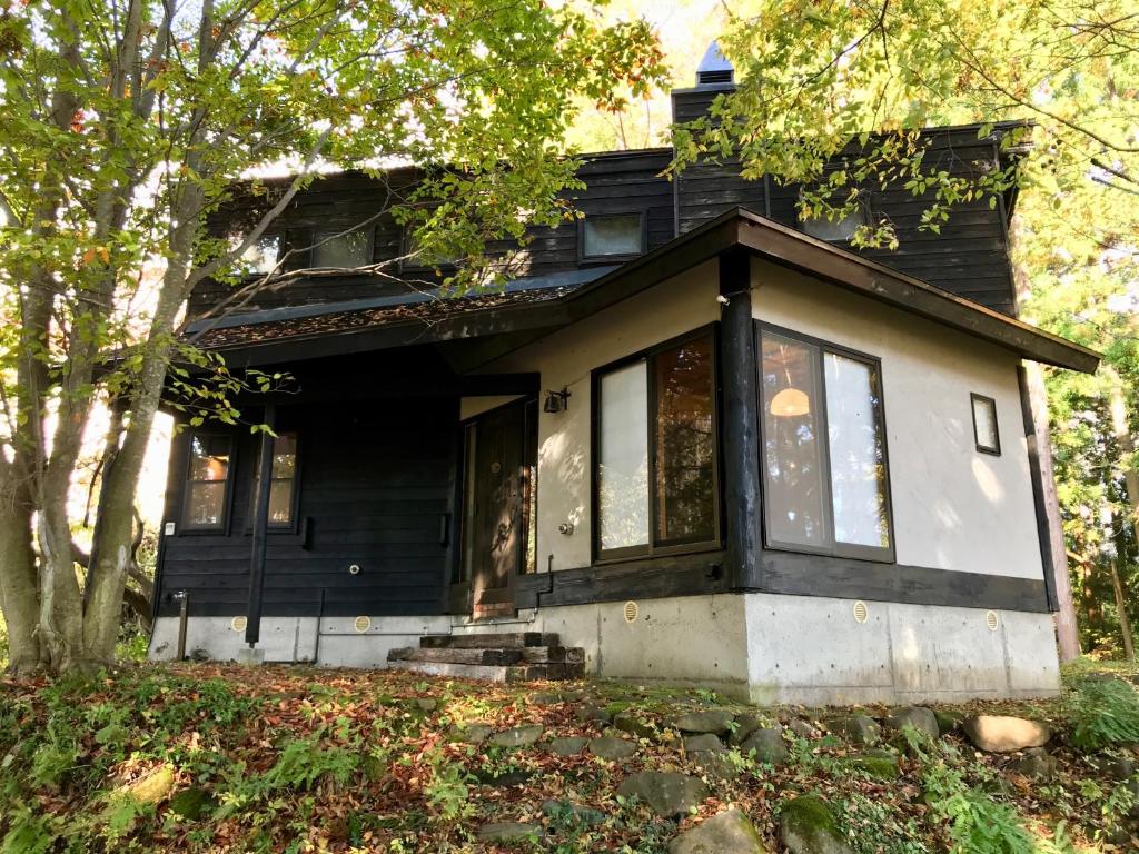 Casa en blanco y negro con porche en Sunnsnow Kallin Cottage en Nagano