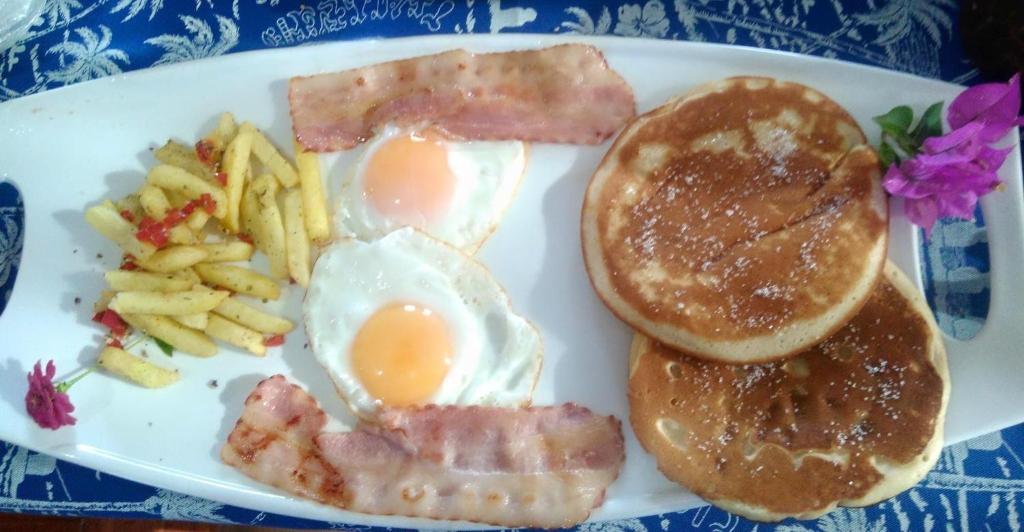 a plate with eggs bacon and pancakes and french fries at Atavai Hotel Rapa Nui in Hanga Roa