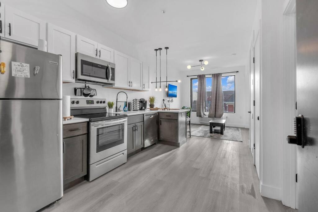 una cocina con electrodomésticos de acero inoxidable y armarios blancos en Luxe 1BDRM Apartment EWR Prudential Center, en Elizabeth