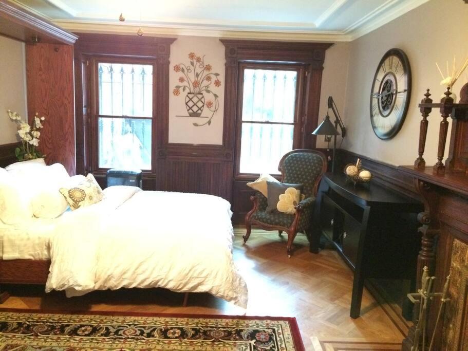 a bedroom with a bed and a desk and windows at Garden Apartment with Private Entry in Brooklyn