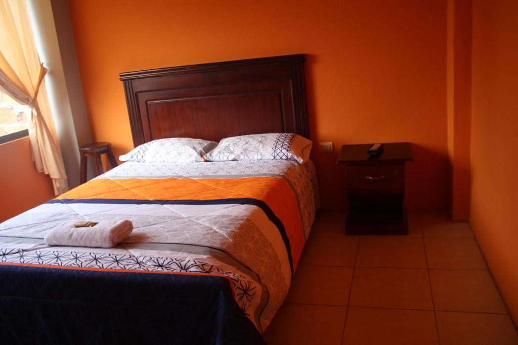 a bedroom with a bed with an orange wall at Centro Macas in Macas