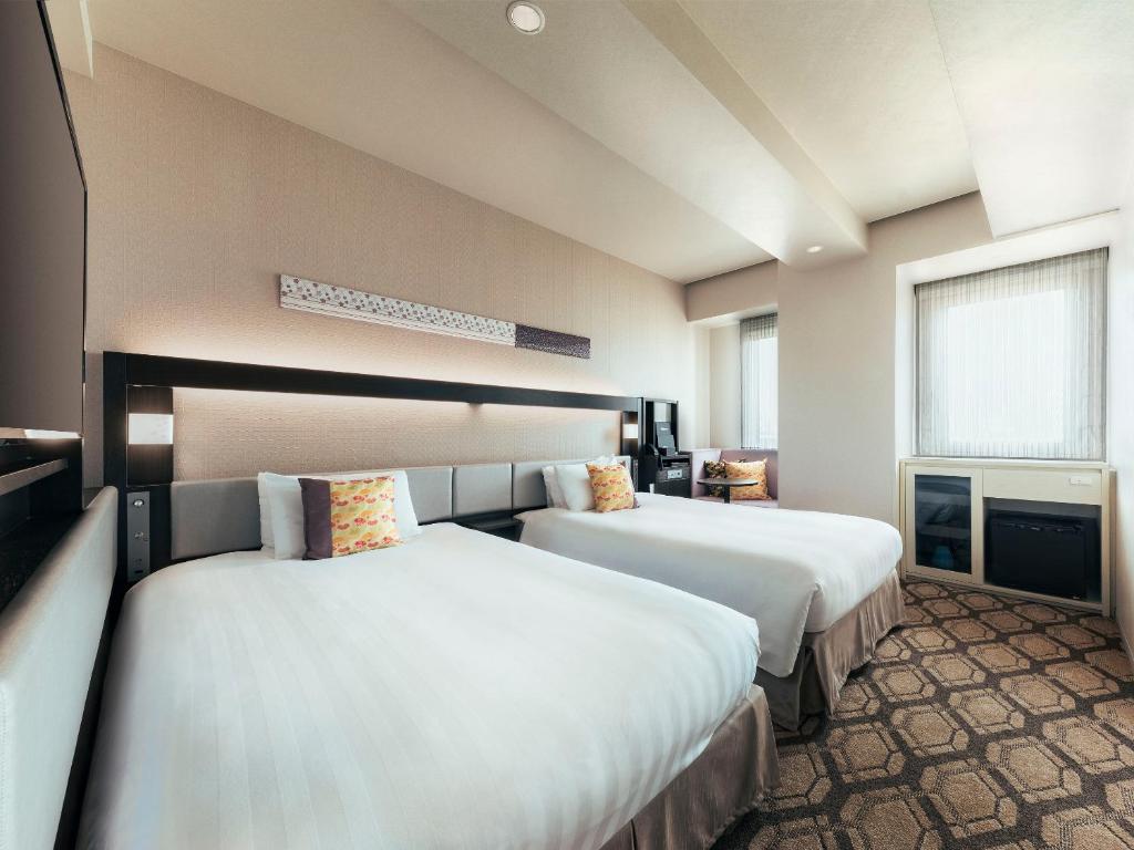 a hotel room with two beds and a window at Hotel Hanshin Annex Osaka in Osaka