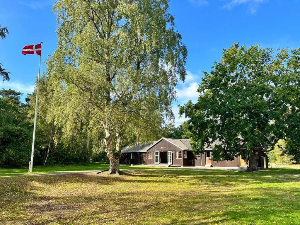 a house with a flag in front of a tree at Holiday home Aakirkeby VI in Vester Sømarken