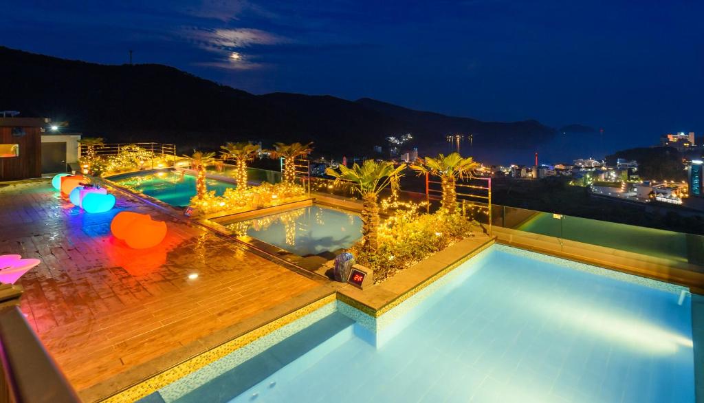 una vista de dos piscinas en el techo por la noche en Friemily Pool Villa & Hotel, en Geoje