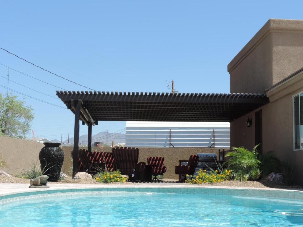 哈瓦苏湖城Sunny Ridge Elegance的一座房子旁的游泳池,配有凉棚和椅子