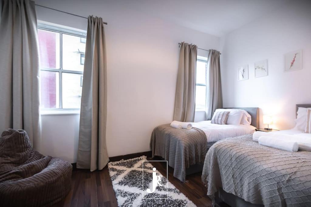 a bedroom with two beds and a chair and a window at The Port Solent City Apartment - Southampton, Portsmouth in Southampton