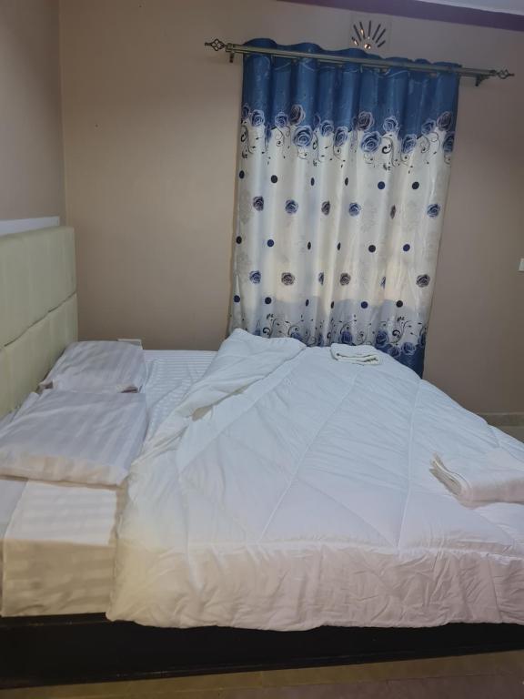 a bedroom with a white bed with a blue curtain at Christa's haven in Siaya